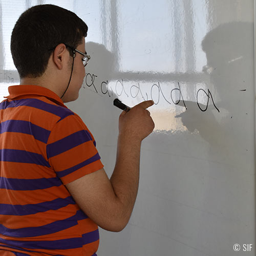 Un élève syrien en train d'apprendre l'alphabet